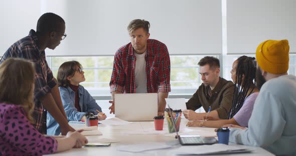 Young Handsome Leader Presenting New Project to Colleagues Having Meeting in Creative Office alt