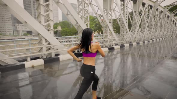Middle-aged Asian woman jogging in the rain in Singapore  alt