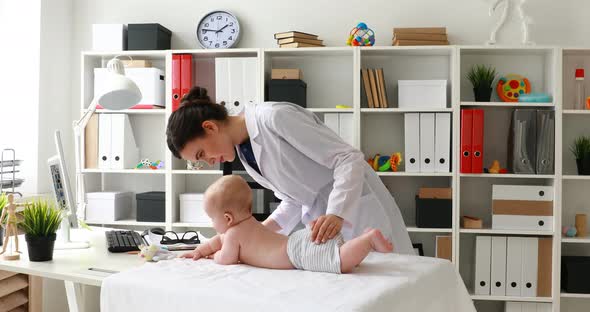 Young Doctor Playing with Baby and Showing Thumb Up on Camera in Office.
