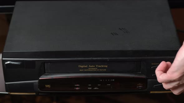 Man Ejecting Video Tape From a VHS Player alt