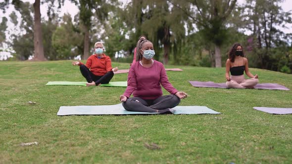 Multiracial people with different generations sitting with social distance and doing yoga