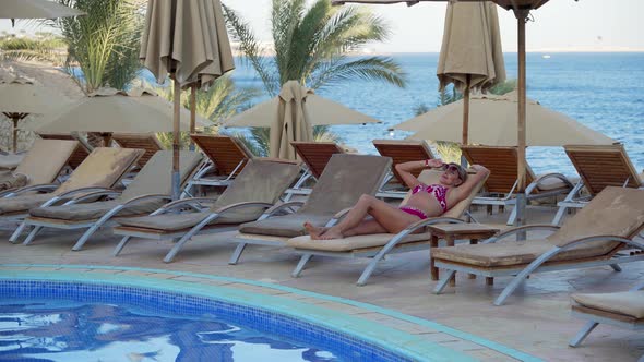 A Middleaged Woman in a Bikini Lies on a Sun Lounger By the Pool By the Sea