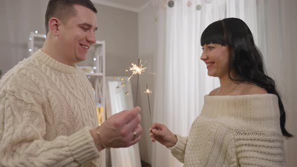 Smiling Happy Young Husband and Wife Holding Sparklers and Talking in Slow Motion on New Year's Day alt