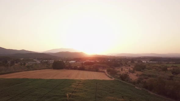 Aerial drone shot flying up showing a magnificent sunset over fields being watered. Tordera, Spain. alt