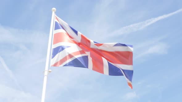 Waving United Kingdom famous striped flag in front of blue sky 4K 2160p 30fps UHD video - Union Jack