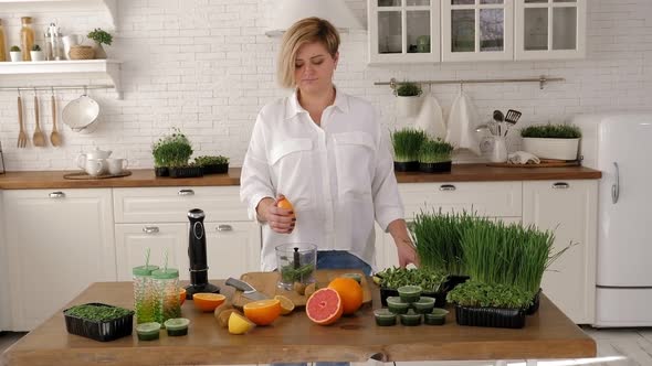 A Young Woman Prepares a Cocktail with Orange Juice and Microgreens alt