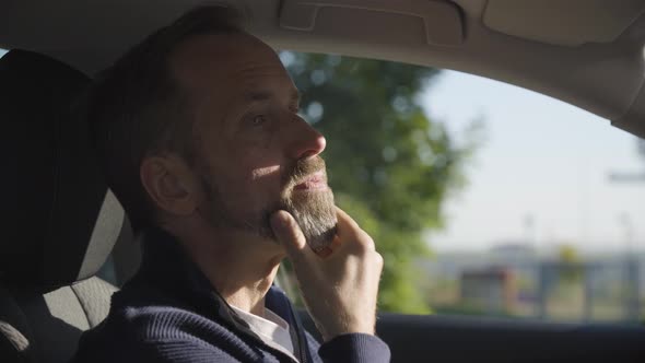 A Middleaged Handsome Caucasian Man Thinks About Something in a Car  Side Closeup