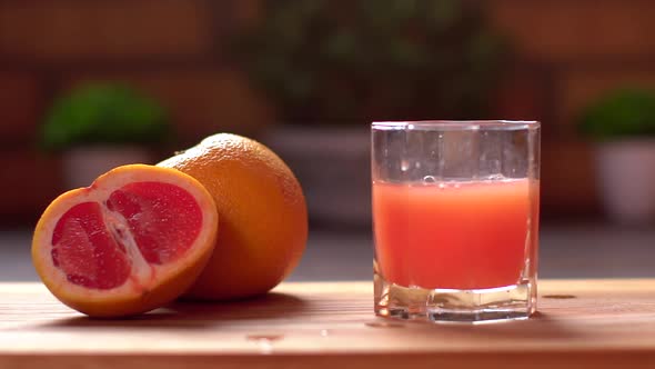 Close-up of Unrecognizable Man Throws Ice Cubes Into a Glass with Fresh Citrus Grapefruit Juice alt