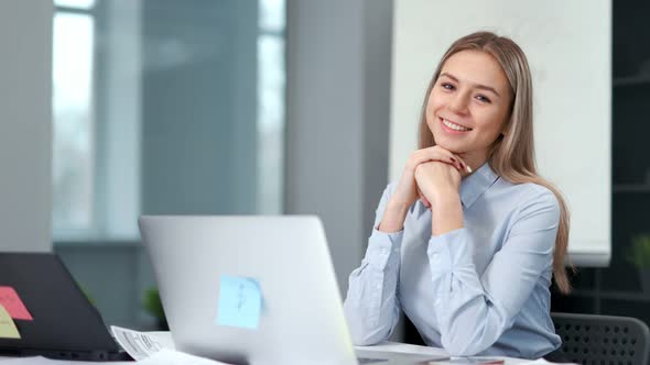 Portrait of Smiling Attractive Young Businesswoman or Office Worker Sitting at Workplace alt
