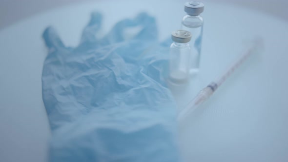Medical Gloves Syringe Medicine Bottle Rotating on the Surface Selective Focus Closeup alt