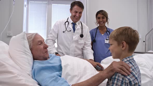 Little Boy Supporting Grandfather in Hospital Ward alt