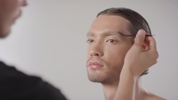Make-Up Artist Combing Eyebrows of Male Model alt