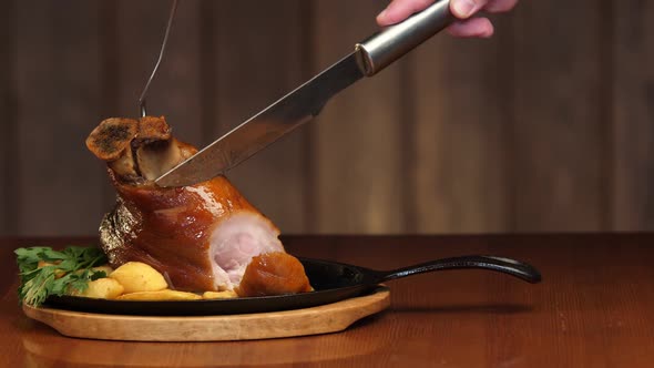 A Man's Hand Cuts an Appetizing Meat Dish Into the Bone with a Knife. Ready Meat Dish with Garnish