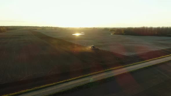 Tractor Working In Fields During Sunset