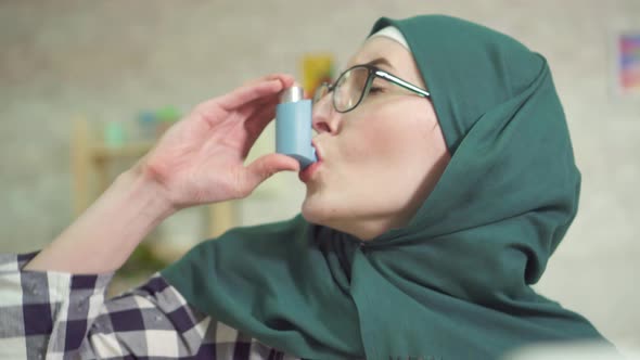 Asthma Attack at Home Use of Asthma Inhaler Woman in Hijab Closeup alt