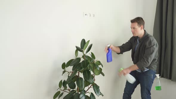 Caucasian Man Spraying Water on House Plant Flower with Spray Bottle at Home