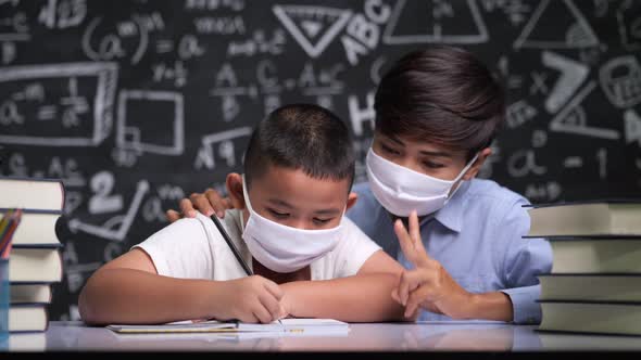 Beautiful female teacher sitting to teach boys to write letters alt