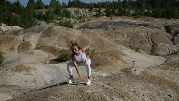Young Woman Squats Outdoors Surrounded By Sand Mountains