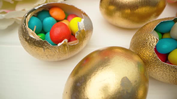 Golden Decorative Easter Eggs Filled with Colorful Candies on Wooden Table Close Up