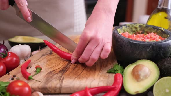 Making Guacamole Sauce  Woman Slicing Chili Pepper on a Wooden Cutting Board alt