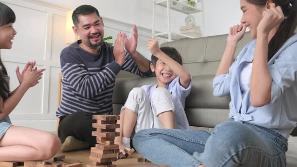 Happy Asian family, parents, and kids are playing with wooden blocks together.