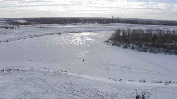 A Fisherman Fishing in Winter Time on Ice Covered River