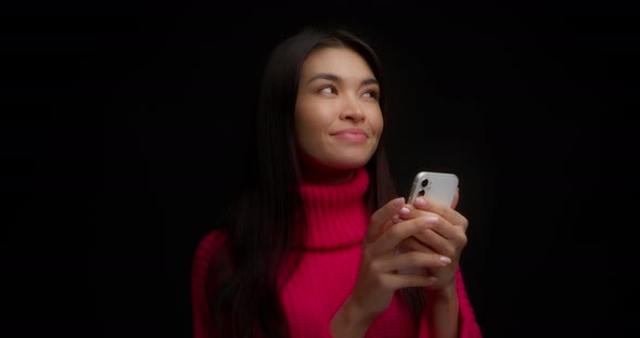 Pretty Asian Woman Thinks What to Answer a Message From a Messenger Smiles