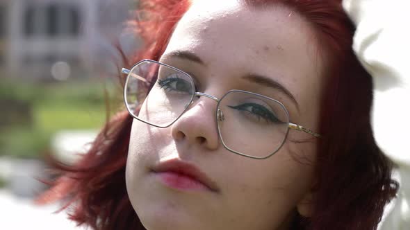Young redhead ukrainian teen girl in glasses on city street