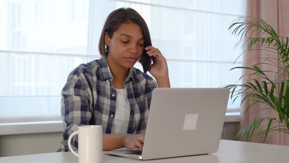 A Young Woman Using a Laptop Communicates on the Internet with a Client at Home