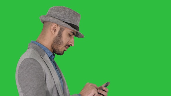 Serious arabic casual man using smartphone while walking alt