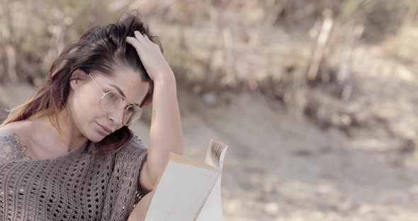 Close-up of a beautiful woman lost in a good book while reading on the beach with copy space alt