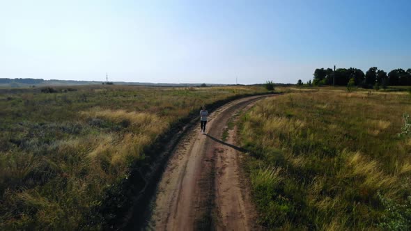 Drone Flies Over Jogger Running on Byroad Rural Area alt