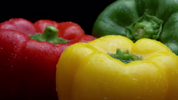 Fresh Raw Yellow, Red, Green, Peppers Rotating On A Black Plate alt