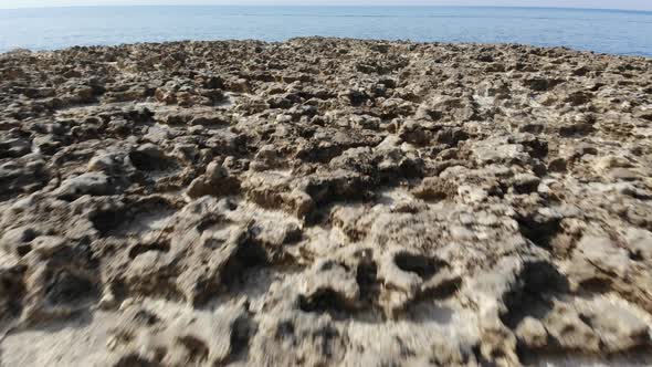 A low-level aerial drone shot flies backward across the Salt Pans of Gozo Island in Malta. alt
