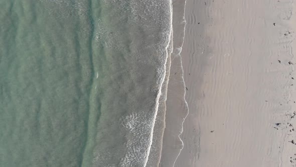 Flakstad beach from above with crashing waves on the sand.