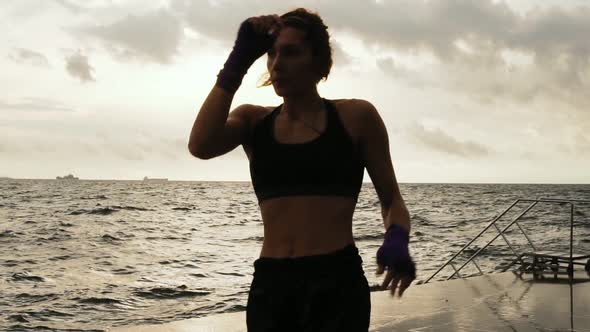 Female Boxer Makes Side Kick of Her Legs Against the Sun By the Sea in Slow Motion alt