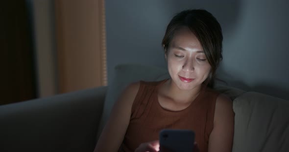 Woman use of mobile phone at home in the evening alt