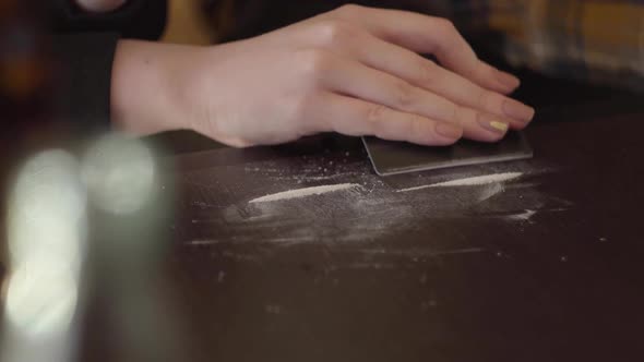 Addict Female Drug Making Cocaine Line with Black Credit Card on Wooden Surface at Home alt