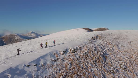 Four Climbers Walk on the Ridge of a Snowy Mountain