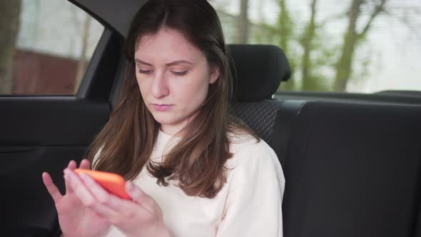 Female Passenger in the Car Looks and Types in the Phone