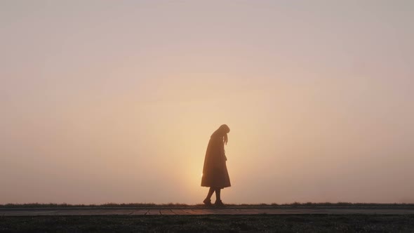 Beautiful Wide Background Shot of Happy Woman Doing Fun Moon Walk Dance at Epic Pink Foggy Sunset alt