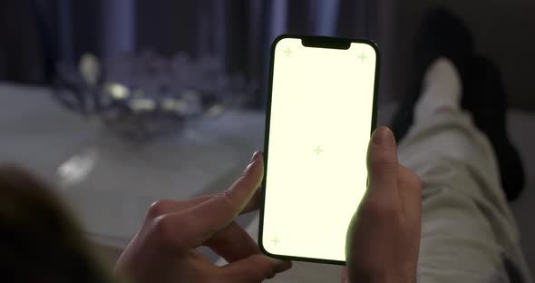 Woman Rests on the Sofa and Uses Smartphone Scrolls Through the Images and Swipe Across the Green alt