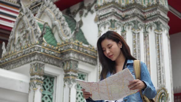 Woman tourist looking at map while exploring ancient Buddhist temple in Bangkok Thailand