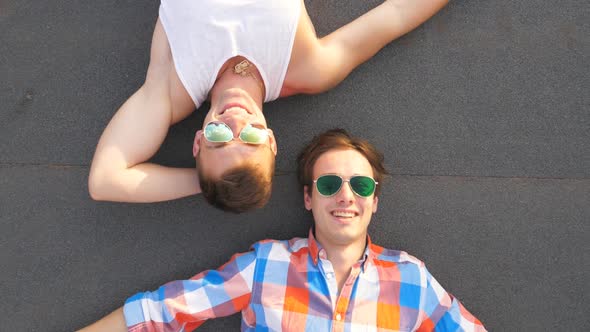 Top View of Two Handsome Guys in Sunglasses Lying with Happiness and Joy Expression on Face alt