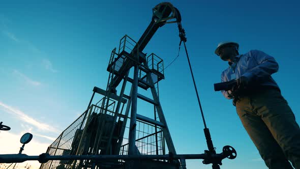 Oil Worker Monitoring Crude Oil Pump Jack. Oil Industry, Crude Oil Prices Concept. alt