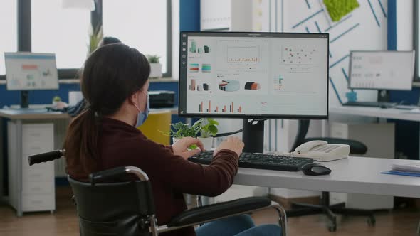 Businesswoman with Face Mask Immobilized in Wheelchair Working at Project alt