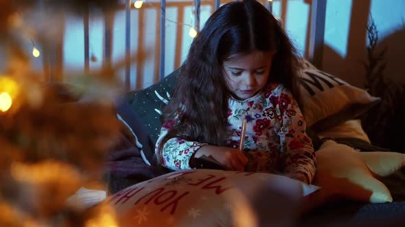 Cute Little Girl Write Letter To Santa on Bed in Room Decorated for Christmas, Christmas Eve alt