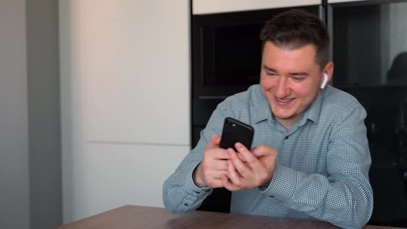 Portrait shot of the excited attractive man 30s dressed in shirt sitting at home and playing games alt
