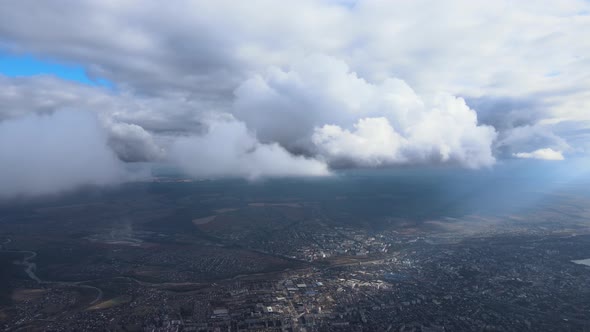 Aerial View From Airplane Window at High Altitude of Distant City Covered with Puffy Cumulus Clouds alt