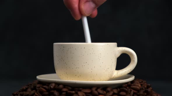 Stirring hot coffee cup with spoon.